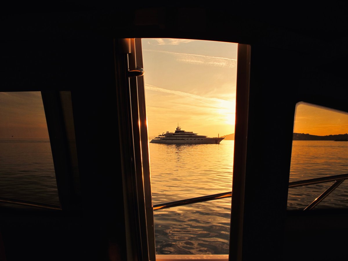 Yacht at sea through elegant framing — golden sunset on the water
