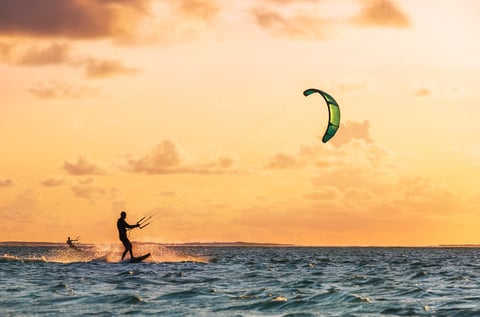 Sunset sky over the ocean bay with kiteboarders riding — private ocean movement experiences Los Cabos
