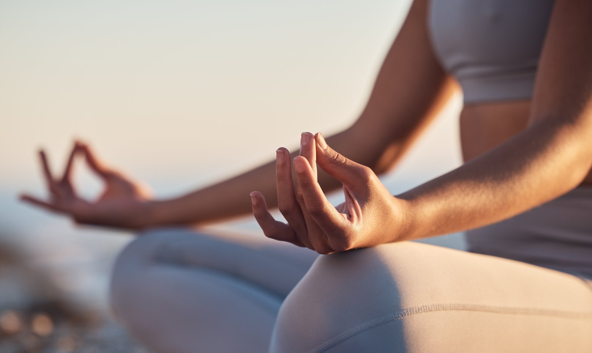 Woman in lotus meditation pose on sunset beach ocean