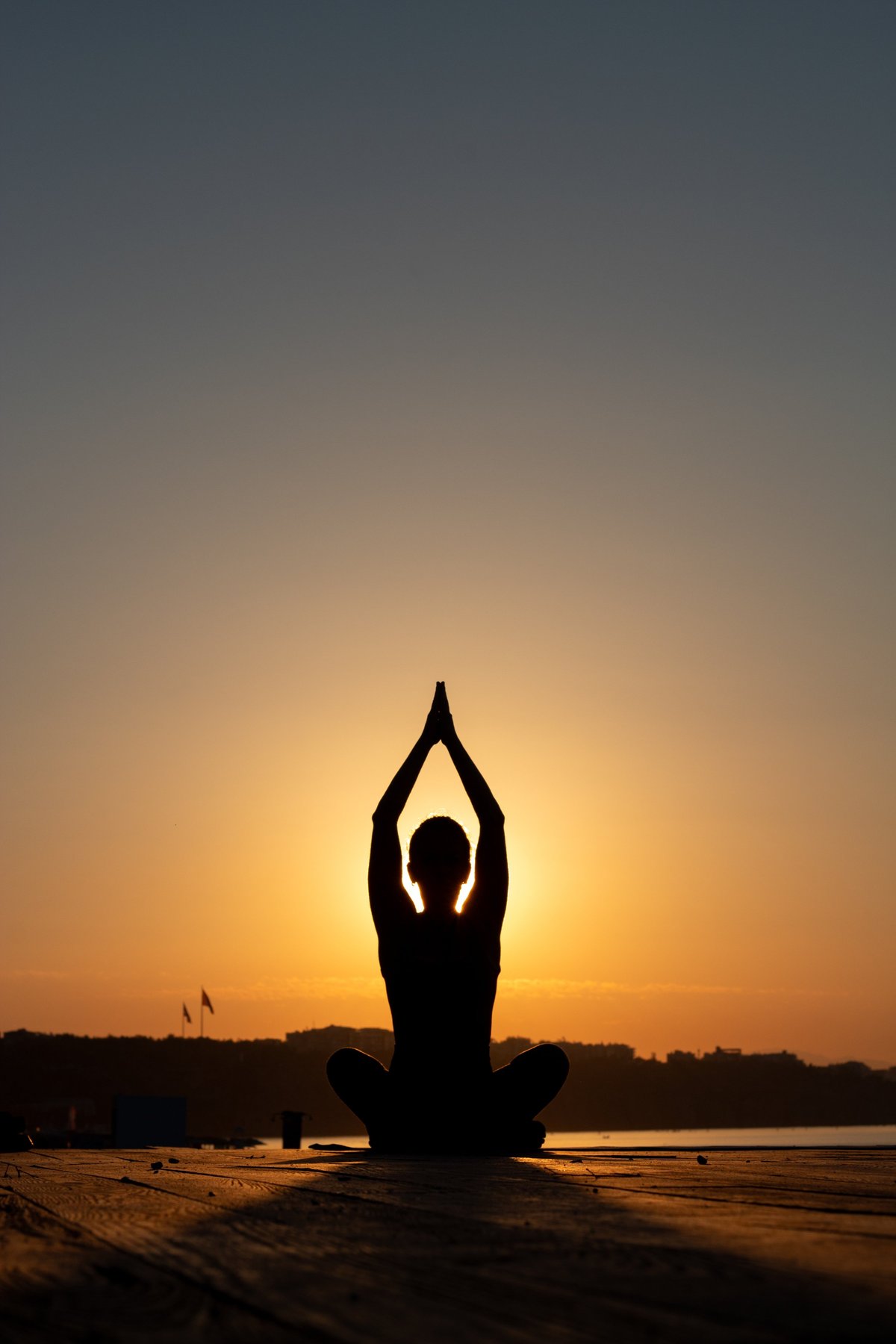 Silhouette of a woman practicing yoga at sunrise with morning light