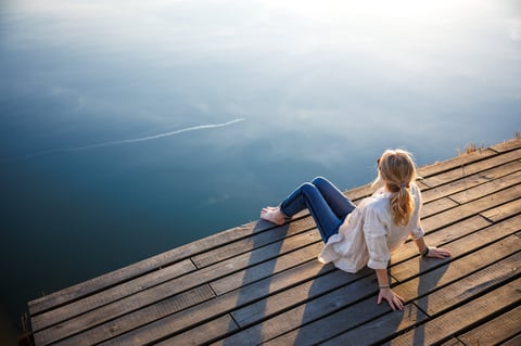 Woman relaxing on a pier, tranquil moment of mindfulness in nature
