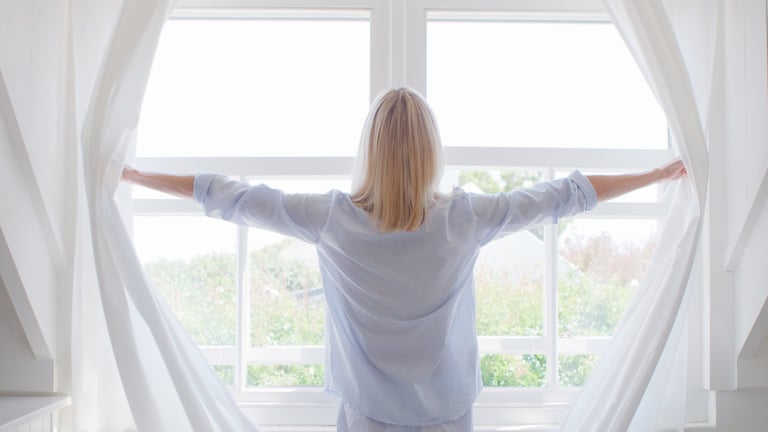 Mujer junto a la ventana en calma matinal