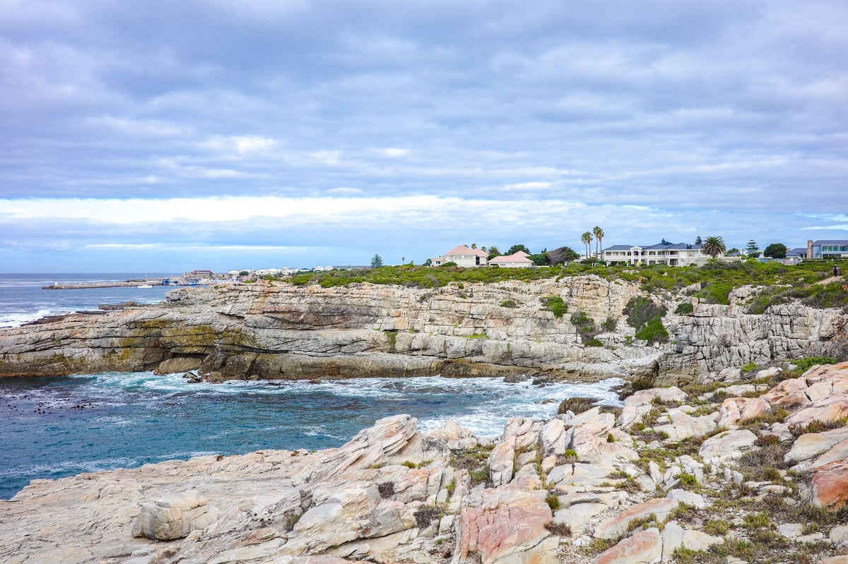 Coastal cliffs overlooking oceanfront houses in Los Cabos with palm trees