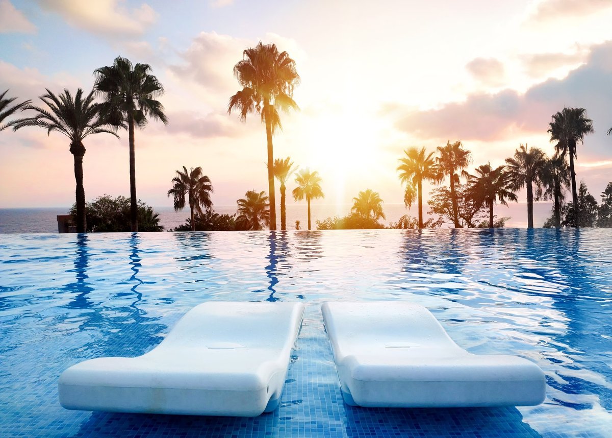 Tranquil sunset over infinity pool with palm trees — luxury wellness and resort living in Cabo