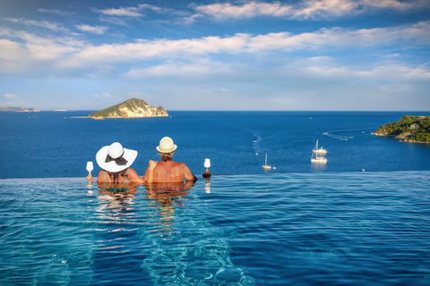 Couple in pool watching sunset over the sea