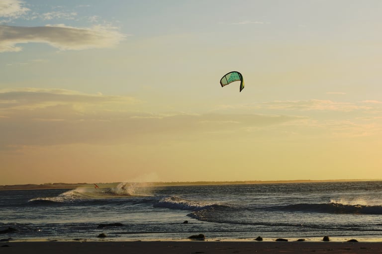 Kiteboarding in sunset light, crispy sea water, wind in yellowish light reflections sky — ocean wellness Los Cabos