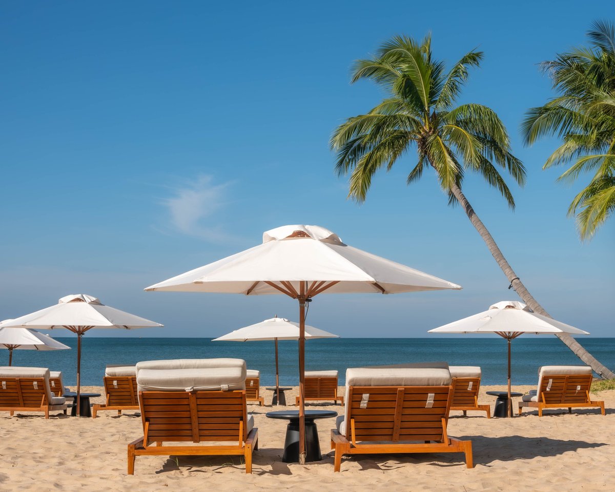 Serene tropical beach with wooden lounge chairs and white umbrellas — luxury coastal living in Cabo
