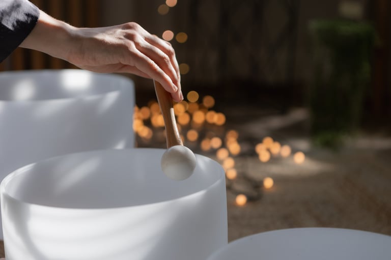 Close up of hand with mallet touching crystal singing bowl in soft natural light — sound healing Los Cabos