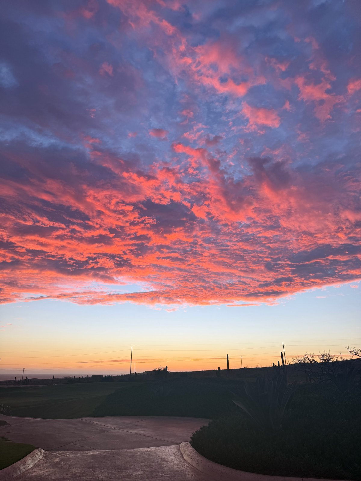 Dramatic sunset over rural landscape with vibrant orange and pink clouds reflected in a winding river below